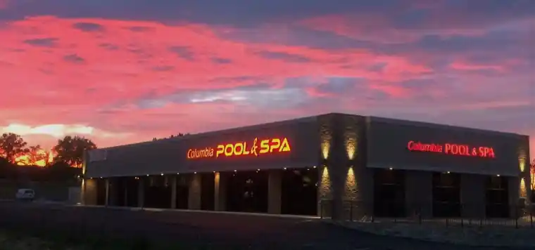 The Columbia Pool & Spa showroom on Business Loop 70 at sunset with its sign lit