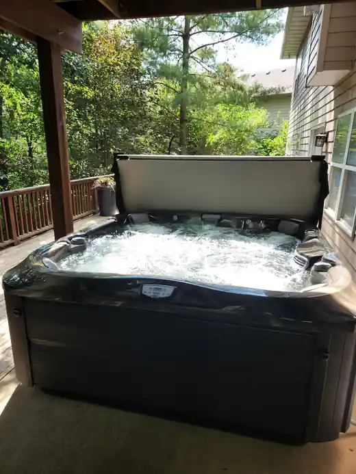 A hot tub on a wooded deck with trees behind it