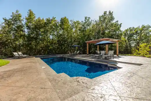 Pool with a pergola and a stamped concrete deck