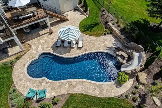 Aerial view of a freeform pool with a slide and a striped umbrella