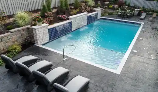 Rectangular pool with a tile water wall, sheer descents and loungers