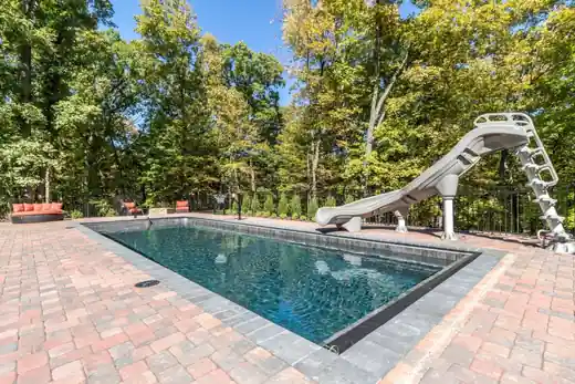 Rectangular pool with a paver deck and a slide