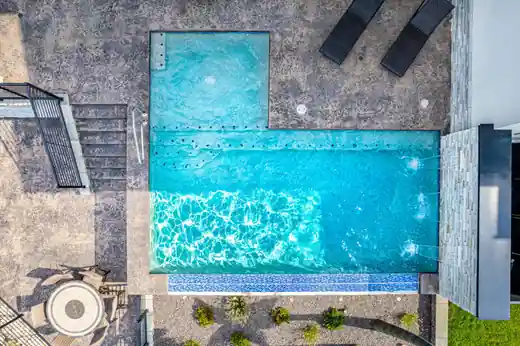 Overhead view of an L-shaped pool with a tile band at the waterline and steps into the shallow end
