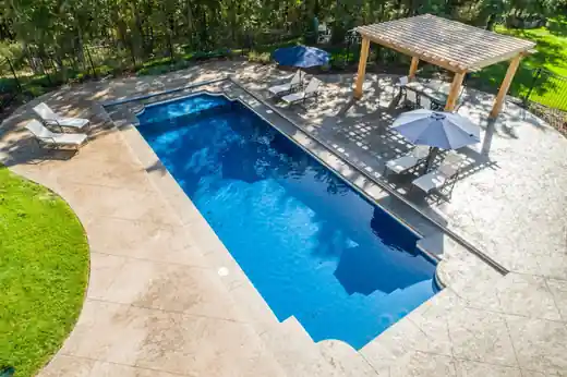 Aerial view of a blue fiberglass pool with a pergola