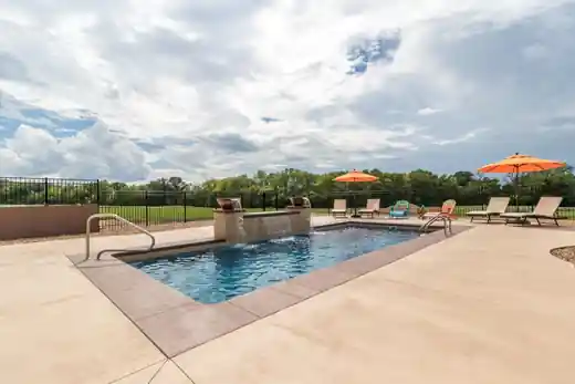 Rectangular pool with orange umbrellas and a water feature