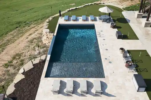 Aerial view of a pool with turf and loungers