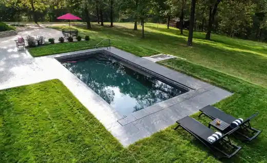 Aerial view of a pool in a lawn with an umbrella