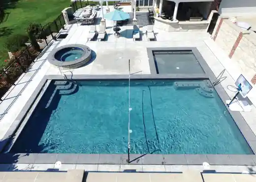 Aerial view of a rectangular pool with a square spa and benches