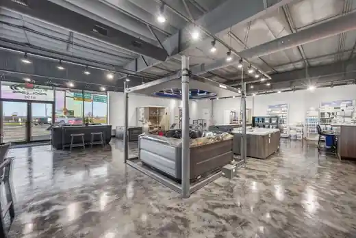 A hot tub under a steel frame canopy on the showroom floor with the front windows behind it